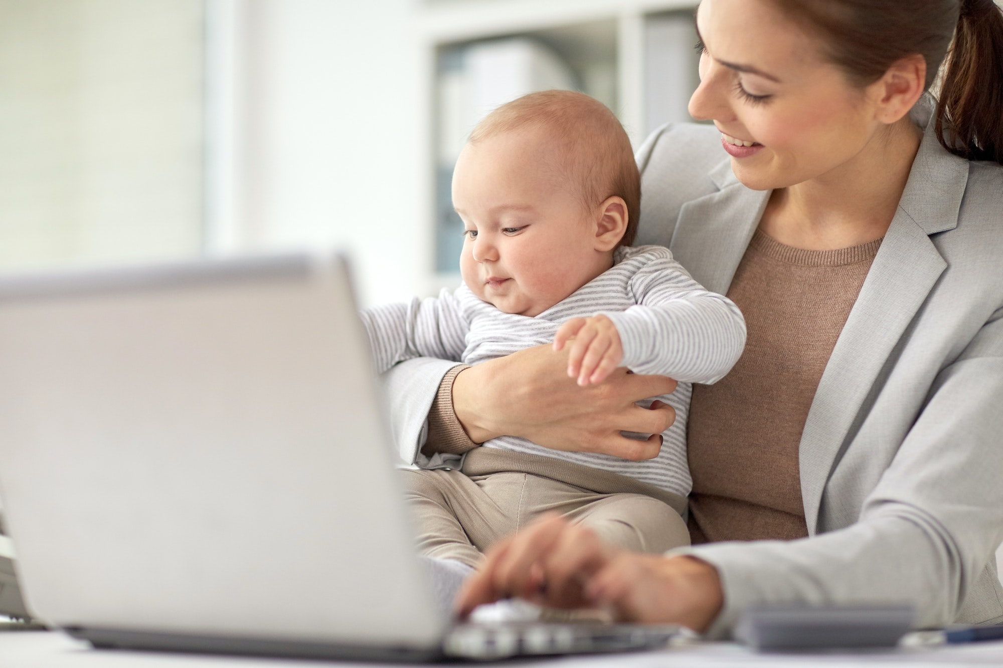 happy businesswoman with baby and laptop at office